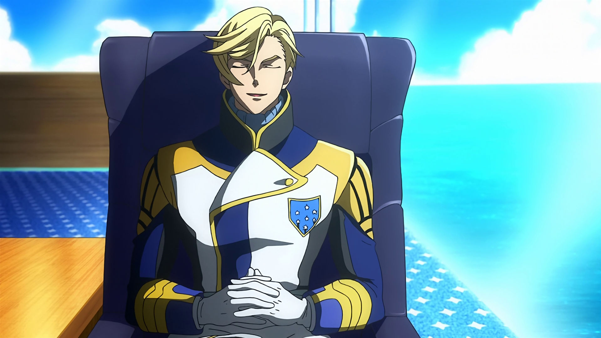 McGillis sitting in a chair with his eyes closed and chuckling.