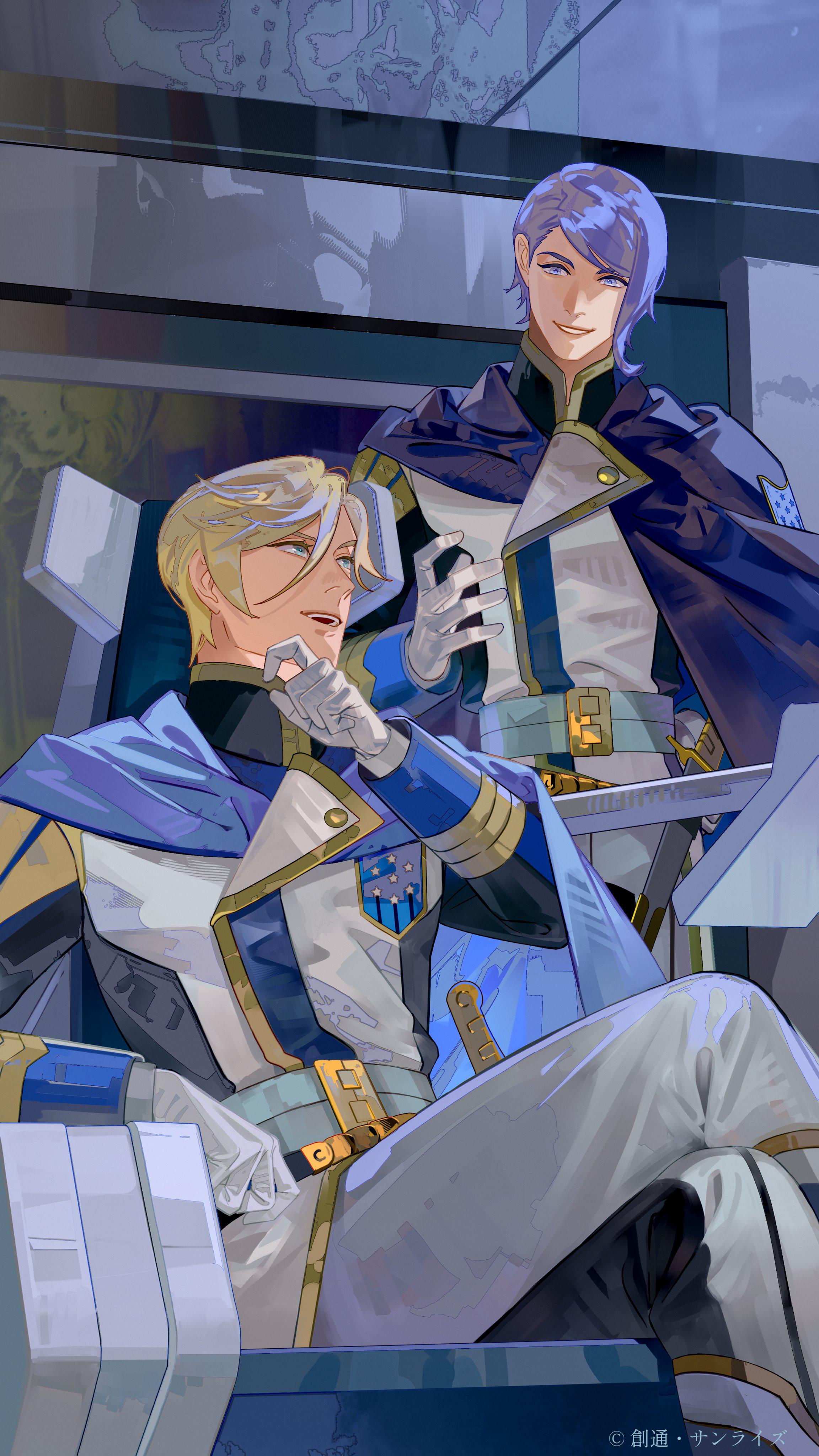 McGillis sitting in a chair, talking to Gaelio who is standing up besides him