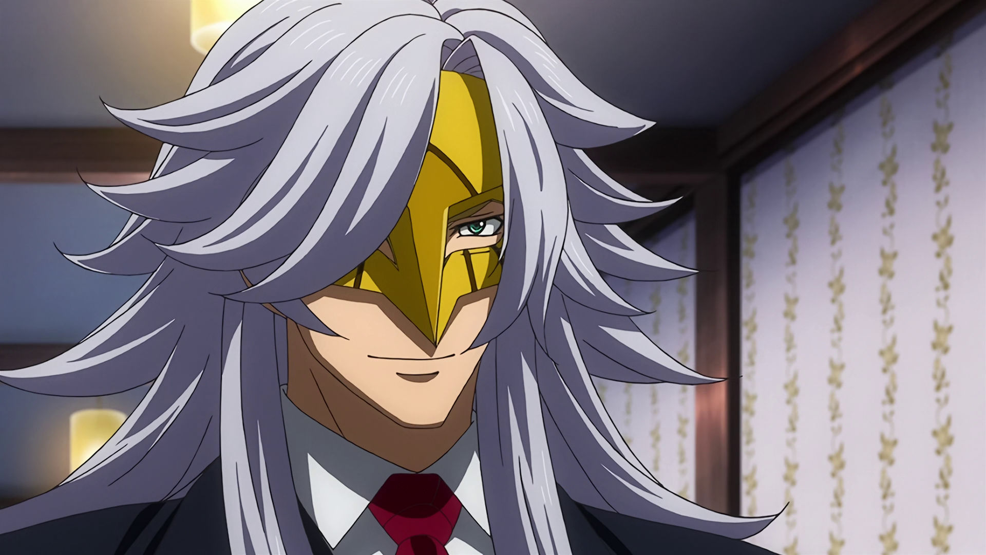 McGillis wearing a golden mask with long gray hair, his eyes are now visible and he is smiling. 